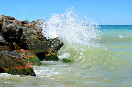 浪花拍打在沙滩上的大石头上照片