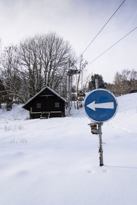上月底在下雪的冬天山滑雪缆车蓝色方向交通标志