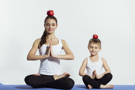 母亲和儿子做瑜伽 体育锻炼，玩得开心，一起共度美好时光。上白孤立。健康的生活方式的概念