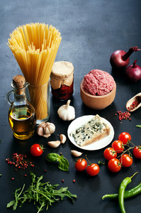 意大利食品的概念。成分为烹饪面食，如面条，洋葱，番茄，橄榄油，地面牛肉 罗勒叶和奶酪在黑板上。用于写入的文本的地方