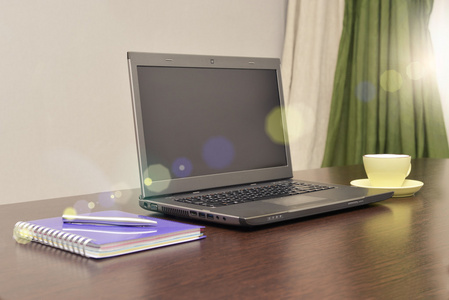 笔记本电脑通讯簿 杯子和钢笔在桌子上。太阳耀斑