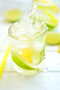 鸡尾酒的柠檬和酸橙用水飞溅的玻璃