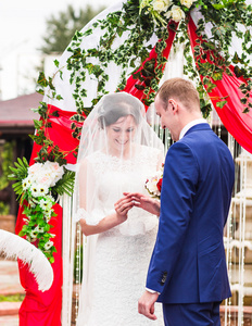 在婚礼服装交换戒指与背景上拱图片