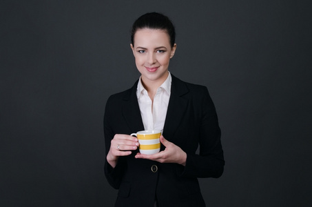 微笑的职业女性，在黑色的背景，咖啡杯上的肖像