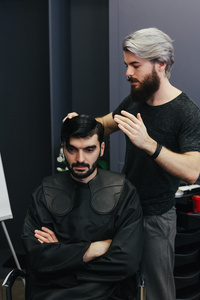 男理发师的梳理和剃光头发的男性客户端