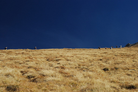 徒步旅行者在陡峭干燥草甸