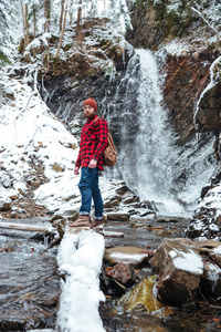 背包里站在山瀑布附近在冬天的男人