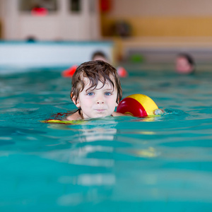 swimmies 学习在室内游泳池游泳的小小孩男孩