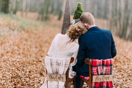 婚礼夫妇坐和拥抱在秋天的树林中的假期表