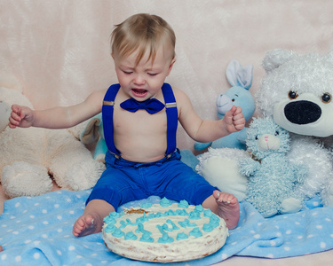 小男孩一边哭一边吃生日派对蛋糕