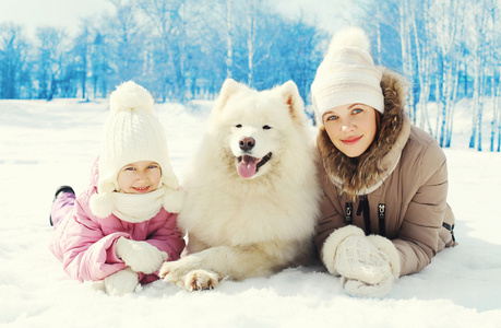 肖像母亲和儿童提供白色的萨摩耶犬一起说谎