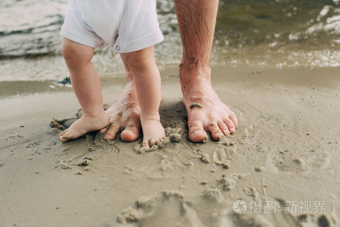 光着脚的父亲和他的小儿子住在附近的水沙