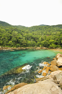 热带海滩以绿化水面 岸边和底部的石头