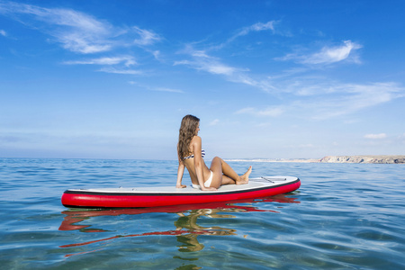 女人坐在一个桨冲浪板