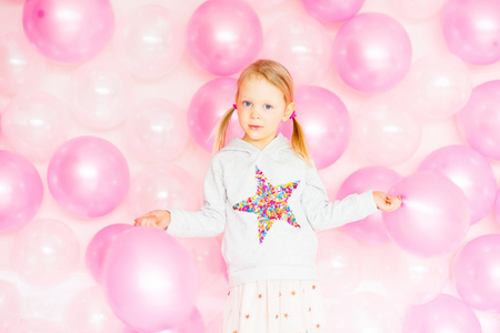小女孩玩着粉红色的气球