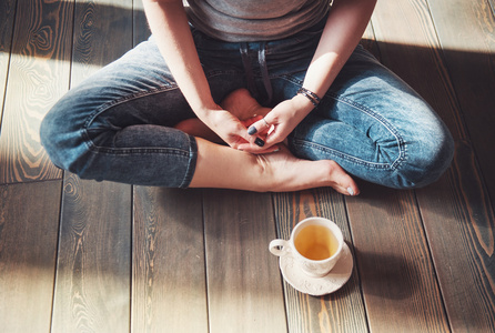 年轻女子与杯茶坐在地板上的温馨照片