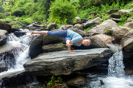 女人做瑜伽 oudoors 在热带瀑布