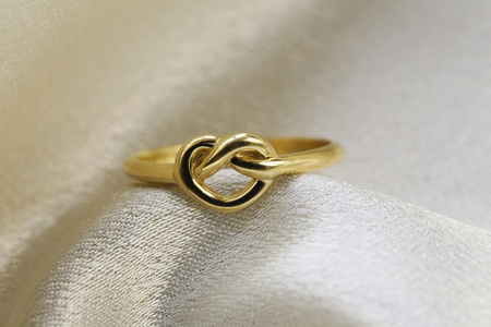 形式的心在米色的丝绸上的金戒指