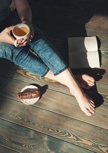 年轻女子与杯茶坐在地板上的温馨照片