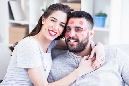 情人节的情侣.女人吻男人与他的脸,浅景深的红色唇膏照片