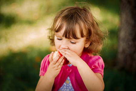 在公园里可爱的小女孩吃苹果