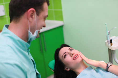 女病人交谈男性牙医和牙科诊所处牙痛的抱怨