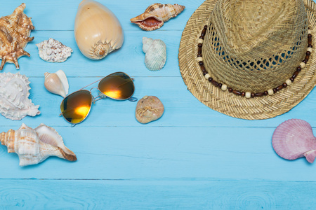 贝壳 帽子和太阳镜上蓝色的木制背景