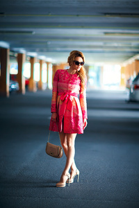美丽的年轻女孩的时尚照片穿着奢华的粉红色礼服, 袋子在地下停车场