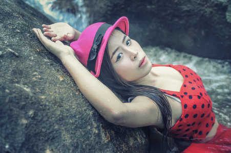 亚洲年轻漂亮性感的女孩躺在岩石上