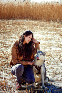 美丽的年轻女子抱着一只哈士奇狗。.针锋相对