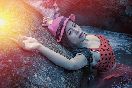 亚洲年轻漂亮性感的女孩躺在岩石上