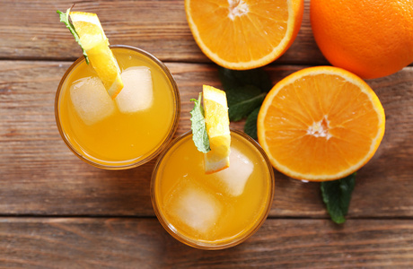 两个橙果汁与冰和木桌背景上的橙色查看从上面