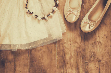复古雪纺女孩打扮，花卉头饰旁边芭蕾舞鞋在木制的背景上。经过筛选，棕褐色的复古风格图像