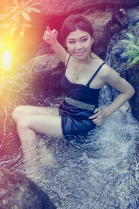 亚洲美丽年轻的女孩坐在水落