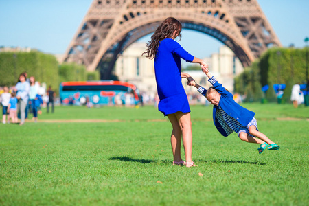 快乐妈妈和小可爱的女孩在巴黎埃菲尔铁塔附近玩得开心