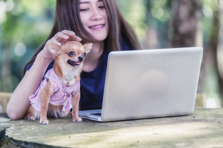 年轻快乐的女人与她的狗和笔记本电脑