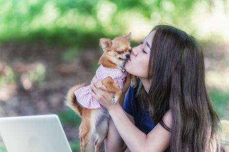年轻快乐的女人与她的狗和笔记本电脑