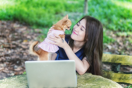 年轻快乐的女人与她的狗和笔记本电脑