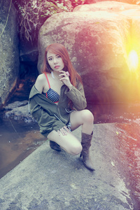 亚洲美丽年轻的女孩坐在岩石上