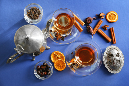玻璃杯茶和茶壶配肉桂和柠檬在蓝色的背景下，顶视图