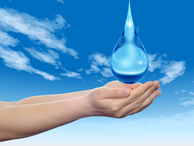 概念或概念的蓝色水或液体滴在两个女人手中落在蓝蓝的天空背景上