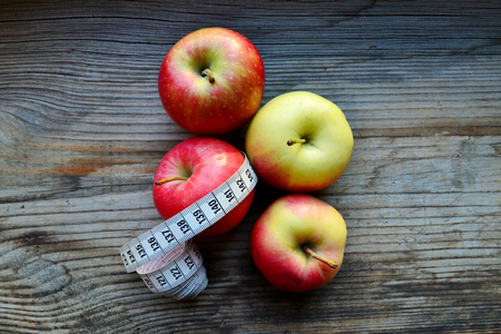 红色和黄色的苹果与白色木制的桌子上卷尺饮食概念