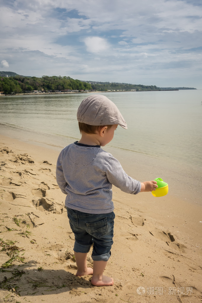 可爱的小男孩在沙滩上玩喷壶