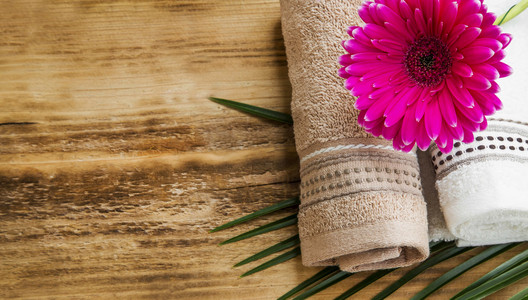 水疗中心设置用毛巾和粉红色的花上木制背景