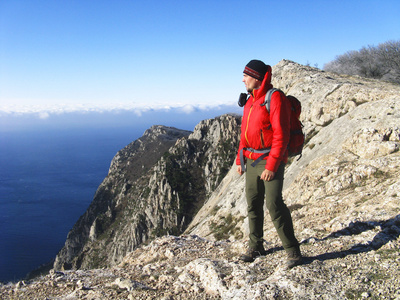 一名男子站在悬崖上看着大海在山与海的背景下