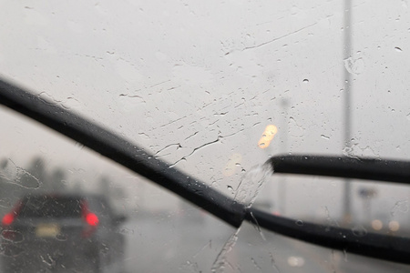 在大雨中, 挡风玻璃雨刷在交通模糊的挡风玻璃上运动