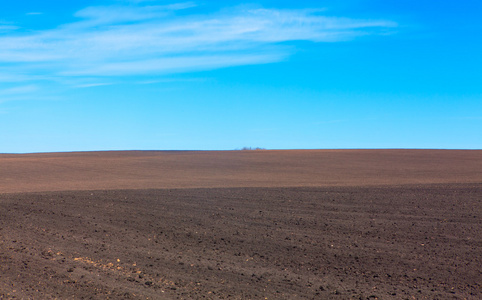 犁过的土地上空的蓝天照片