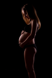 在黑色背景上的年轻孕妇