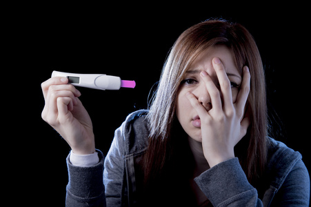 年轻女人害怕和震惊持有妊娠试验阳性结果看起来不开心