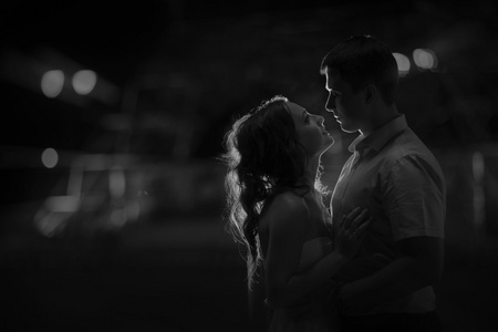 夫妇站在一把抱住面对彼此，晚上照片，黑色和白色